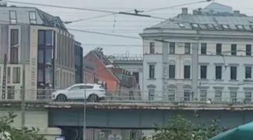 Rīdzinieki uz pauzes. Centrā mašīna pārvietojas pār dzelzceļa tiltu